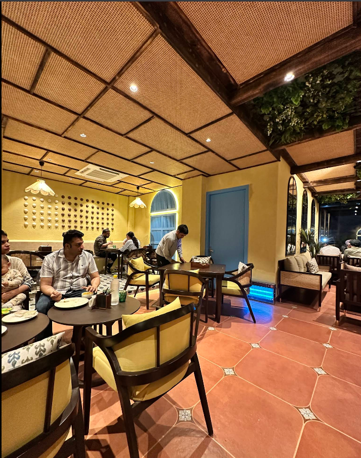 BrewBell warm-lit interior with yellow chairs and terracotta tiles